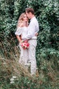 Bride and groom with a bouquet of peonies posing against the backdrop of the forest Royalty Free Stock Photo