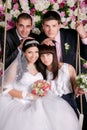 Bride and groom with bridesmaids and groomsmen in studio background from flowers