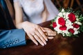 Bride and groom in a cafe. wedding bouquet of roses on a wooden table in a restaurant, bride and groom hold each other`s Royalty Free Stock Photo