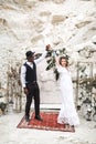 Bride and groom in canyon outdoors. wedding ceremony. boho wedding arch. African man and Caucasian woman in boho wear Royalty Free Stock Photo