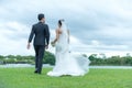 The bride and groom couple in wedding attire with a bouquet of flowers in the hands against the backdrop