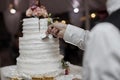 Bride and groom cut rustic wedding cake on wedding banquet with red rose and other flowers