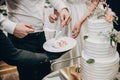 Bride and groom cutting stylish wedding cake at wedding reception in restaurant. Wedding couple holding slice of  wedding cake Royalty Free Stock Photo