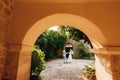 The bride and groom dancing and circling in the coutryard in the old town of Perast, view through the arch