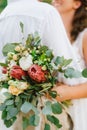 Bride and groom embracing, bride holding wedding bouquet of proteas, roses and eucalyptus in her hand