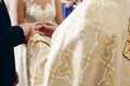 Bride and groom exchanging golden wedding rings at wedding ceremony in christian church, priest putting on wedding ring on sensual