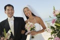 Bride and Groom with flowers on beach (portrait) Royalty Free Stock Photo