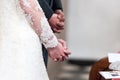Bride and groom folding hands in church