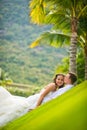 Bride and groom gentle kiss on the lawn on a background of palm trees Royalty Free Stock Photo