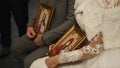 Bride and groom get married in church. They listen to cleric holding icons in their hands
