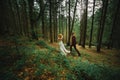 The bride and groom go through the forest hand in hand. Happy bride and groom holding hands and walking in forest on wedding day Royalty Free Stock Photo