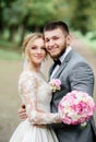 Bride and groom in grey suit look gorgeous posing in a bright summer forest