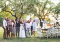 Bride, groom, guests posing for the photo at wedding reception outside in the backyard. Royalty Free Stock Photo