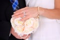 Bride and groom hands with brides hand sat atop flowers Royalty Free Stock Photo