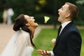 Bride and groom having fun trying to catch with their mouthes a Royalty Free Stock Photo