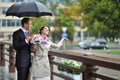Bride and groom hiding from the rain, while catching raindrops a