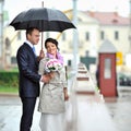 Bride and groom hiding from rain in an old town Royalty Free Stock Photo