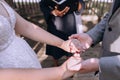 A bride and groom hold each other's hands during an outdoor wedding ceremony