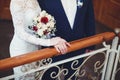 The bride and groom hold hands gently at the wedding, standing on the stairs, close-up