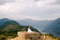 The bride and groom hold hands on the roof of the Gorazda fort, behind them a view of the Bay of Kotor