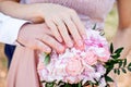 bride and groom hold hands, sunny day, hands with wedding rings close-up on a background of a bouquet of roses. Royalty Free Stock Photo