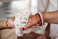 The bride and groom hold hands tied with a garland of white flowers. Beautiful traditional Indian wedding ceremony. Hindu wedding Royalty Free Stock Photo