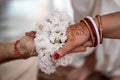 The bride and groom hold hands tied with a garland of white flowers. Beautiful traditional Indian wedding ceremony Royalty Free Stock Photo