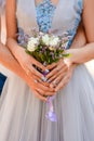 The bride and groom hold in their hands a cute wedding bouquet closeup of white roses and small purple flowers. Royalty Free Stock Photo