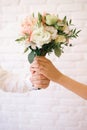 Bride and groom hold a wedding bouquet of flowers, hands of man and woman close up, vertical photo Royalty Free Stock Photo