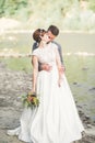 Bride and groom holding beautiful wedding bouquet. Posing near river Royalty Free Stock Photo