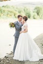 Bride and groom holding beautiful wedding bouquet. Posing near river Royalty Free Stock Photo