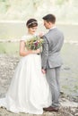 Bride and groom holding beautiful wedding bouquet. Posing near river Royalty Free Stock Photo