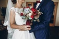 Bride and groom holding bouquet with red roses and succulents. g Royalty Free Stock Photo