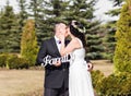 Bride and groom holding bouquet and wooden word family Royalty Free Stock Photo