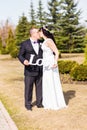 Bride and groom holding bouquet and wooden word love Royalty Free Stock Photo