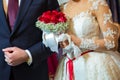 Bride and groom holding bridal bouquet close up . Red roses in brides hands Royalty Free Stock Photo