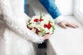 Bride and groom holding bridal bouquet close up. red and white roses, freesia, brunia decorated in composition Royalty Free Stock Photo