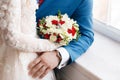Bride and groom holding bridal bouquet close up. red and white roses, freesia, brunia decorated in composition Royalty Free Stock Photo