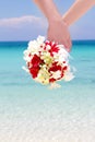 Bride and groom holding bridal bouquet on natural sea background