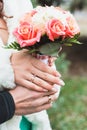 The bride and groom holding a cute wedding bouquet of pink roses and white daisies close up. Royalty Free Stock Photo
