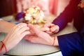 Bride and groom holding hands with wedding rings on the table over the blur bouquet background Royalty Free Stock Photo