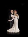 Bride and groom holding an old cake topper on a black background. Figurines for a wedding cake Royalty Free Stock Photo