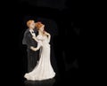 Bride and groom holding an old cake topper on a black background. Figurines for a wedding cake Royalty Free Stock Photo