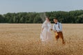 Bride and groom holding wedding champagne glasses on the background of wheat field. Happy wedding couple in wheat field Royalty Free Stock Photo