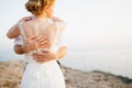 The bride and groom hug on the rocks by the sea against the backdrop of the mountains and the island of Mamula, back