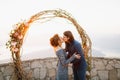 The bride and groom hugging and kissing near the wedding arch on the observation deck overlooking the Bay of Kotor Royalty Free Stock Photo