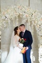 bride and groom kiss in an arch of flowers with a marriage certificate. Royalty Free Stock Photo