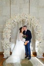 bride and groom kiss in an arch of flowers with a marriage certificate. Royalty Free Stock Photo