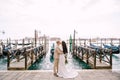 The bride and groom kiss on the gondola pier, hugging, in Venice, near St. Mark`s Square, overlooking San Giorgio Royalty Free Stock Photo