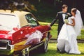 Bride and groom kiss standing in an open vintage car Royalty Free Stock Photo